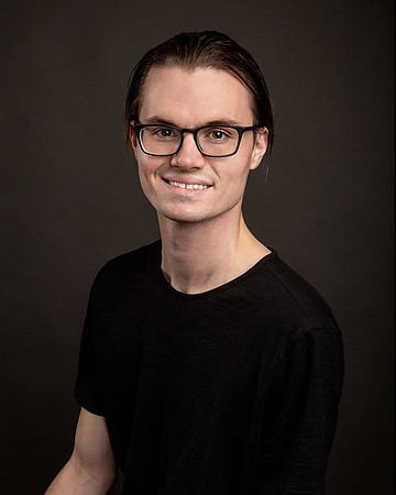 man_headshot_wearing_glasses_darker_background