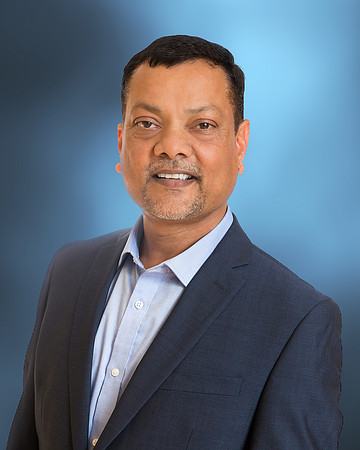 man executive headshot portrait with office blurred blue background