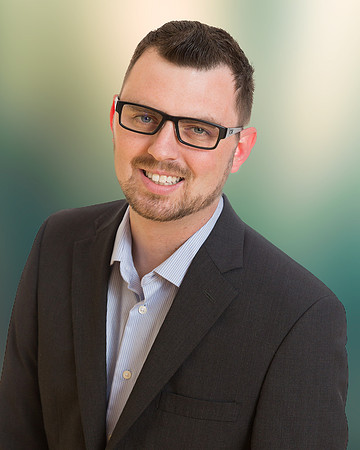 man executive headshot portrait with office blurred green background