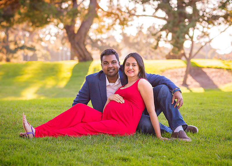 maternity session couple seating on the grass