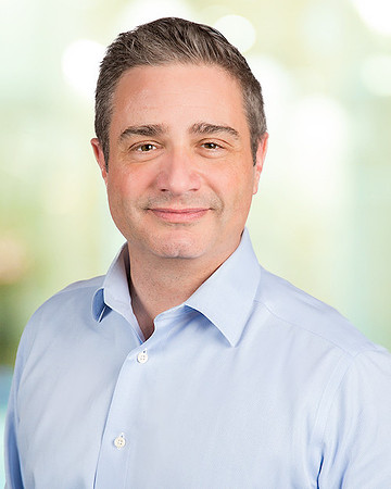 man_headshot_with_blurred_office_yellow_background