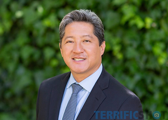 executive_corporate_outdoor_man_headshot_with_green_blurry_background-min