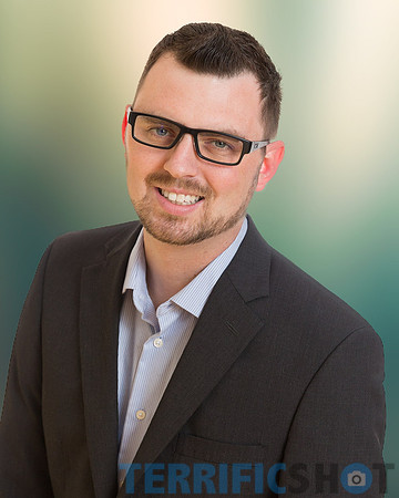 man__with_glasses_headshot_with_yelow_and_green_office_blurred_background-min