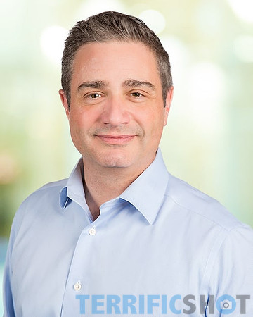 man_headshot_with_blurred_office_yellow_background-min