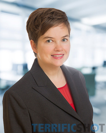 young_woman_with_red_shirt_and_jacket_portrait_corporate_with_blurred_office_background-min